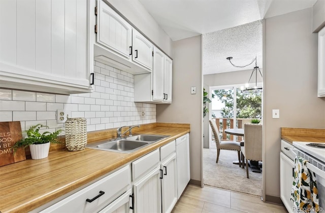 kitchen featuring a sink, tasteful backsplash, a textured ceiling, white cabinets, and light countertops