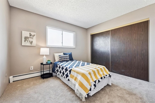 carpeted bedroom with a closet, baseboard heating, and a textured ceiling