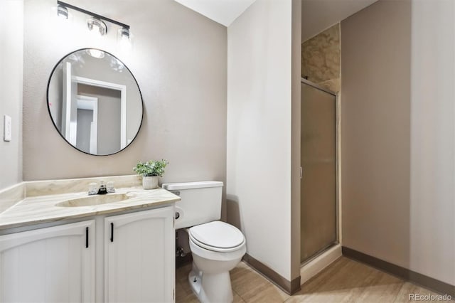 bathroom featuring baseboards, a shower stall, vanity, and toilet