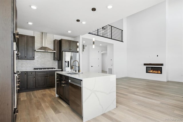 995 Pinehurst Ct, Bennett, CO 80102 - kitchen with wall chimney exhaust hood, stainless steel appliances, light wood-style flooring, hanging light fixtures, and backsplash