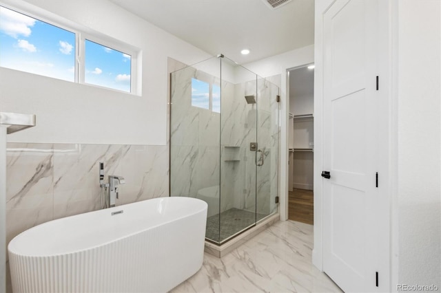 995 Pinehurst Ct, Bennett, CO 80102 - bathroom with a marble finish shower, marble finish floors, a freestanding tub, tile walls, and a walk in closet