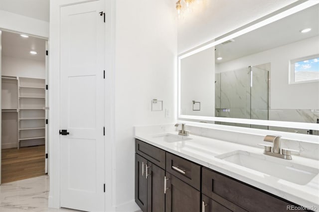 995 Pinehurst Ct, Bennett, CO 80102 - bathroom featuring a marble finish shower, marble finish floors, double vanity, recessed lighting, and a walk in closet