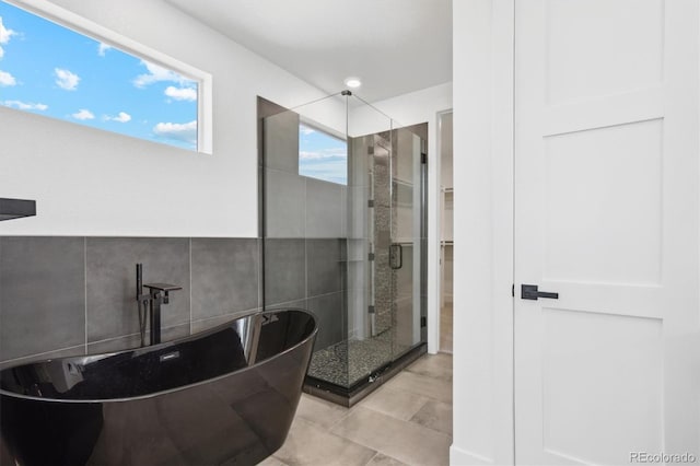 995 Pinehurst Ct, Bennett, CO 80102 - bathroom with a shower stall, a freestanding tub, a walk in closet, tile walls, and tile patterned flooring