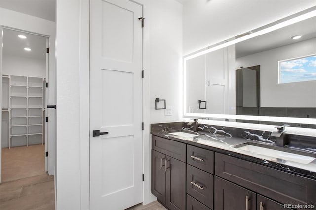 995 Pinehurst Ct, Bennett, CO 80102 - bathroom featuring double vanity, a spacious closet, and recessed lighting