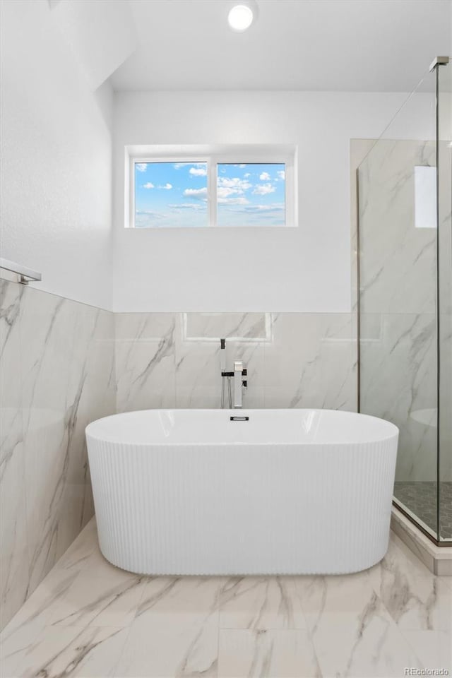 995 Pinehurst Ct, Bennett, CO 80102 - full bathroom featuring tile walls, a soaking tub, marble finish floors, a marble finish shower, and wainscoting