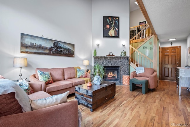15149 E Princeton Pl Unit B, Aurora, CO 80014 - living room with light wood-style flooring, stairs, a tile fireplace, and a textured ceiling