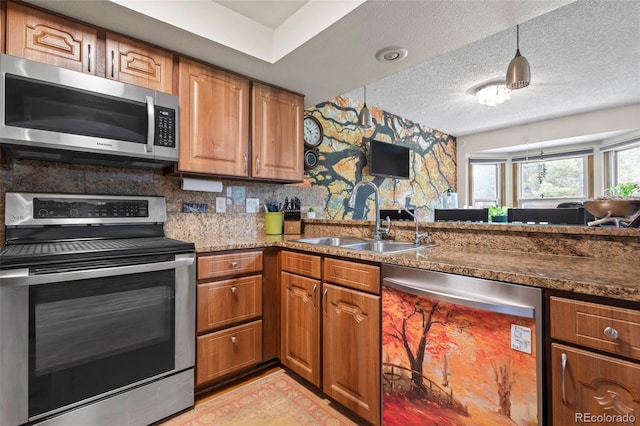 15149 E Princeton Pl Unit B, Aurora, CO 80014 - kitchen with stainless steel appliances, a sink, brown cabinetry, wallpapered walls, and a textured ceiling