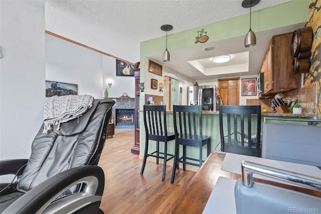 15149 E Princeton Pl Unit B, Aurora, CO 80014 - kitchen with appliances with stainless steel finishes, light wood-type flooring, a fireplace, hanging light fixtures, and a textured ceiling