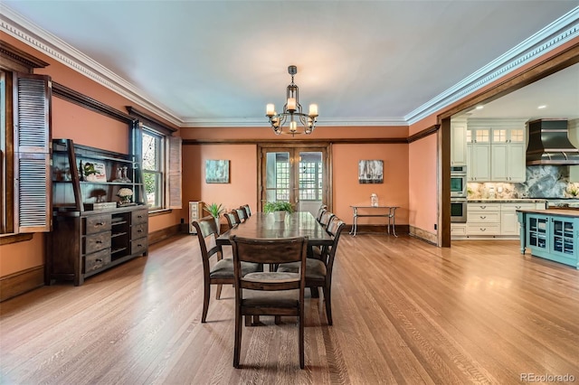 dining space with baseboards, a notable chandelier, ornamental molding, and light wood-style flooring