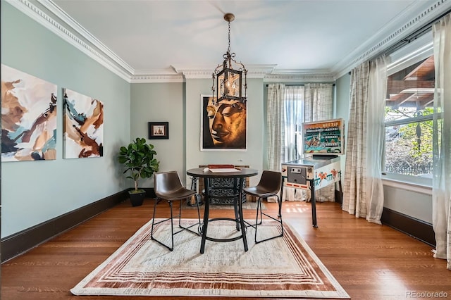 dining area with baseboards, a notable chandelier, ornamental molding, and wood finished floors