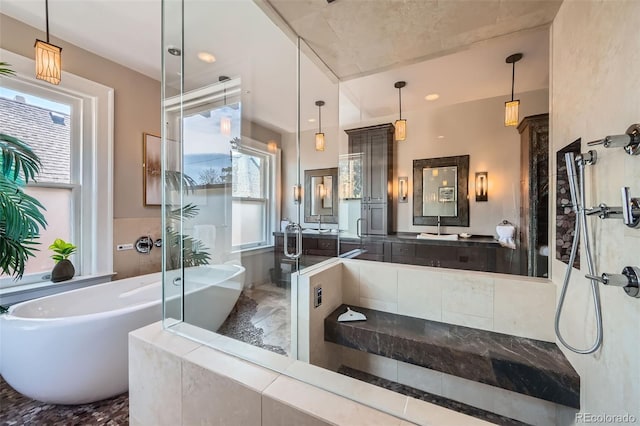 bathroom with a walk in shower, a freestanding bath, and vanity