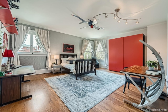 bedroom with crown molding, baseboards, and wood finished floors