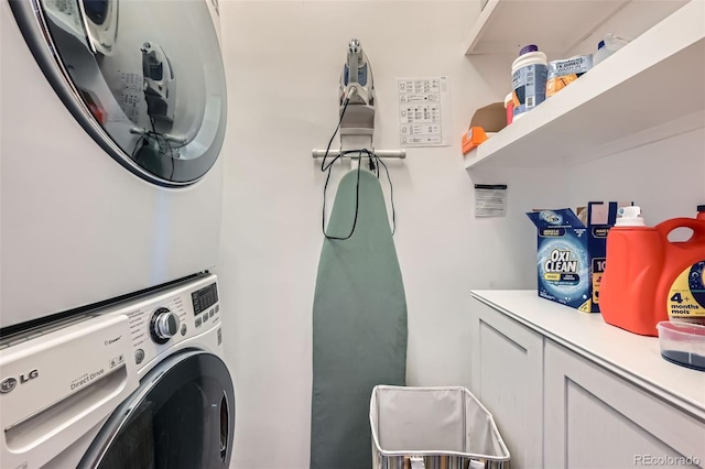clothes washing area with stacked washing maching and dryer and cabinet space