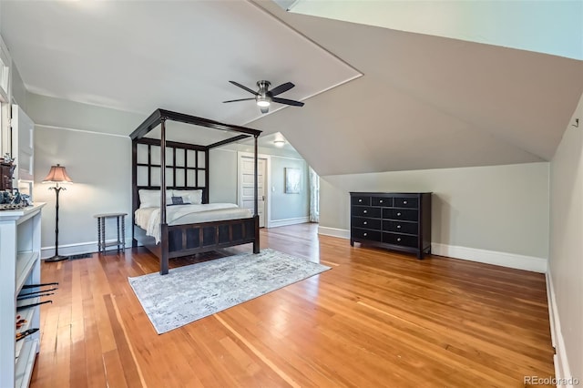 bedroom with light wood-style floors, baseboards, and vaulted ceiling