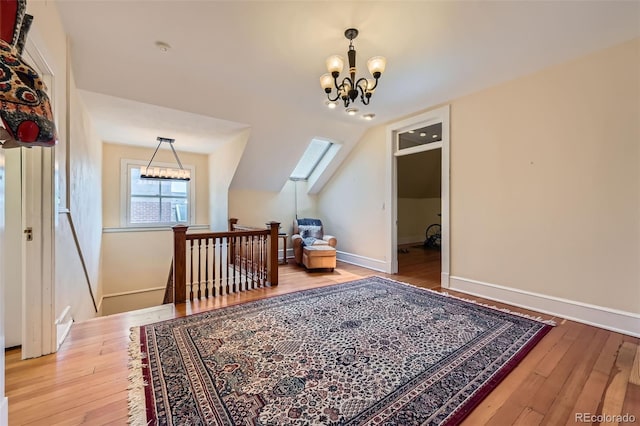 additional living space featuring an inviting chandelier, baseboards, vaulted ceiling, and hardwood / wood-style flooring