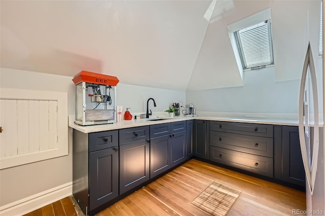 kitchen with stainless steel fridge, a sink, light wood finished floors, light countertops, and gray cabinets