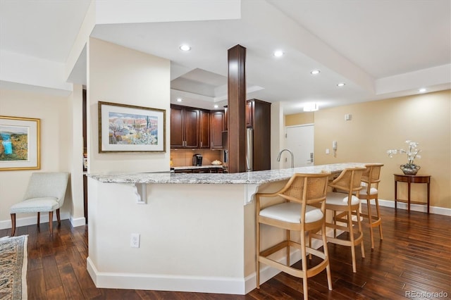 1512 Larimer St Unit 39, Denver, CO 80202 - kitchen featuring a breakfast bar area, paneled refrigerator, dark wood-style floors, light stone counters, and recessed lighting