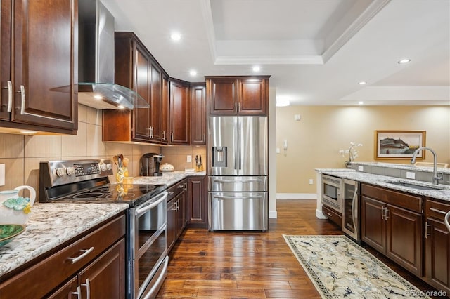 1512 Larimer St Unit 39, Denver, CO 80202 - kitchen featuring stainless steel appliances, wall chimney exhaust hood, a sink, a raised ceiling, and baseboards