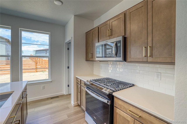 23909 E 41st Ave, Aurora, CO 80019 - kitchen with stainless steel appliances, plenty of natural light, tasteful backsplash, and light wood-style flooring
