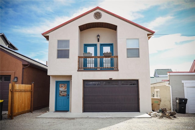 view of front of property with stucco siding, a balcony, a garage, and fence