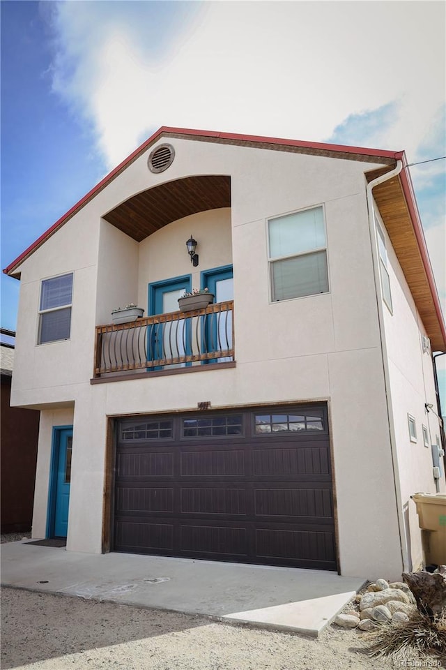 view of front facade with stucco siding, a balcony, and a garage