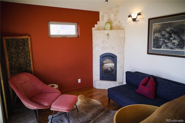 living area with a tiled fireplace, wood finished floors, and vaulted ceiling