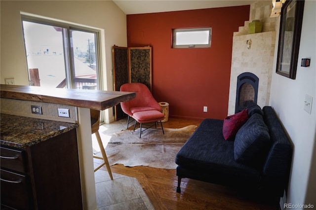 sitting room featuring wood finished floors, a fireplace, and vaulted ceiling