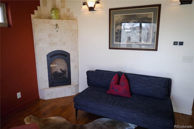 living area with wood finished floors, baseboards, and a tile fireplace