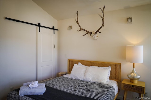 bedroom with a barn door and lofted ceiling