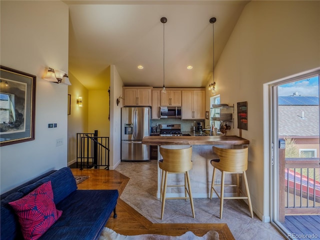kitchen with stainless steel appliances, a peninsula, light brown cabinets, and baseboards