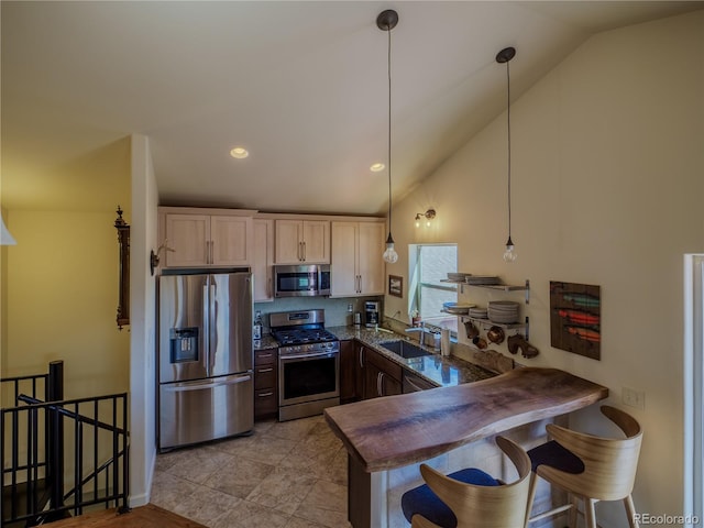 kitchen with decorative light fixtures, a sink, a kitchen breakfast bar, a peninsula, and stainless steel appliances