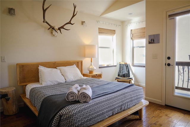 bedroom with multiple windows, baseboards, and wood finished floors