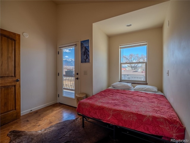 bedroom featuring access to outside, baseboards, and wood finished floors
