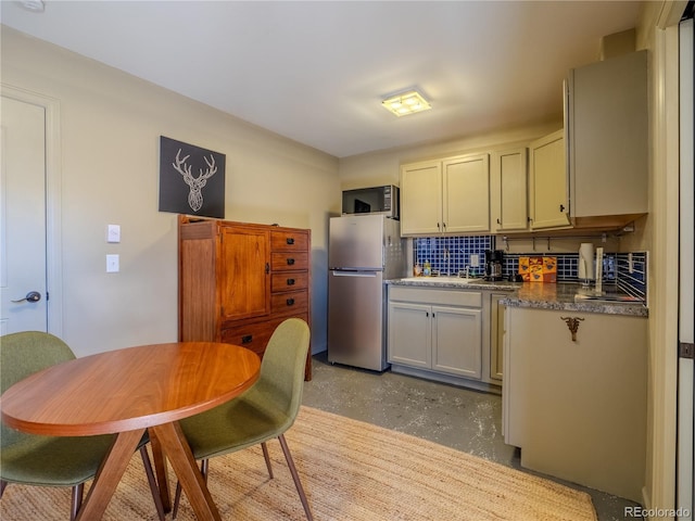 kitchen featuring tasteful backsplash, concrete floors, and freestanding refrigerator