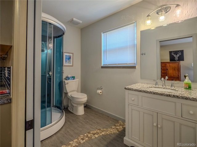 full bathroom with visible vents, toilet, vanity, wood finished floors, and a stall shower
