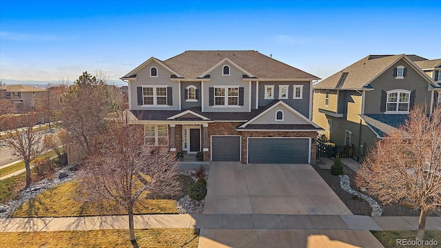 traditional-style house featuring roof with shingles, concrete driveway, an attached garage, and fence