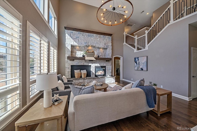 living room featuring a towering ceiling, baseboards, a fireplace, and dark wood-style flooring