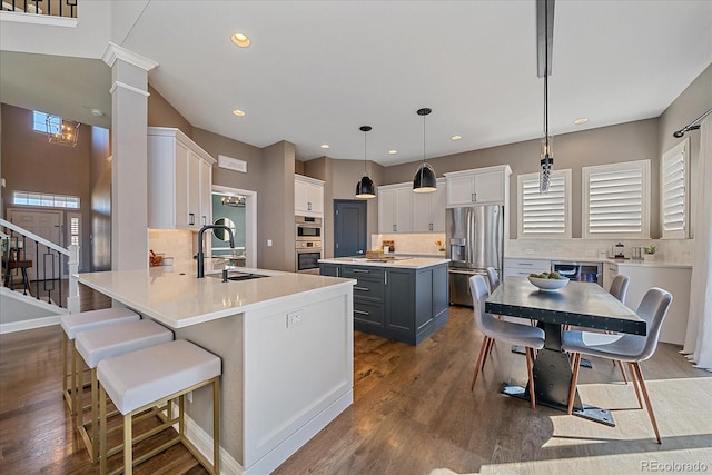 kitchen featuring tasteful backsplash, dark wood finished floors, appliances with stainless steel finishes, a peninsula, and a sink