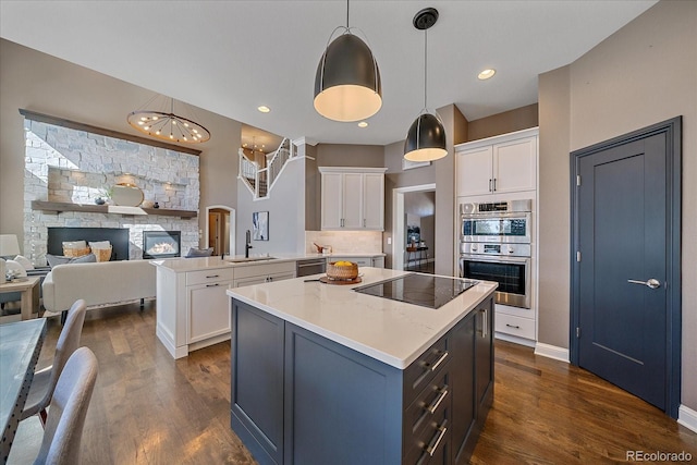 kitchen with dark wood-style floors, a kitchen island, a peninsula, stainless steel appliances, and white cabinetry