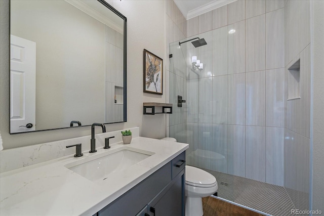 bathroom featuring vanity, toilet, crown molding, and a tile shower