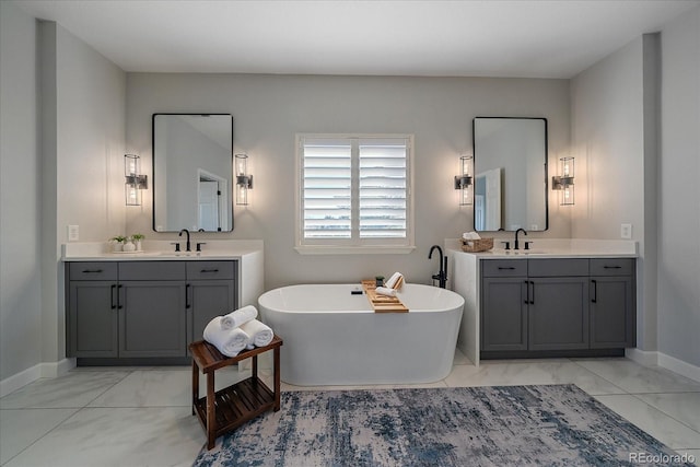 bathroom with a sink, a freestanding tub, two vanities, and marble finish floor