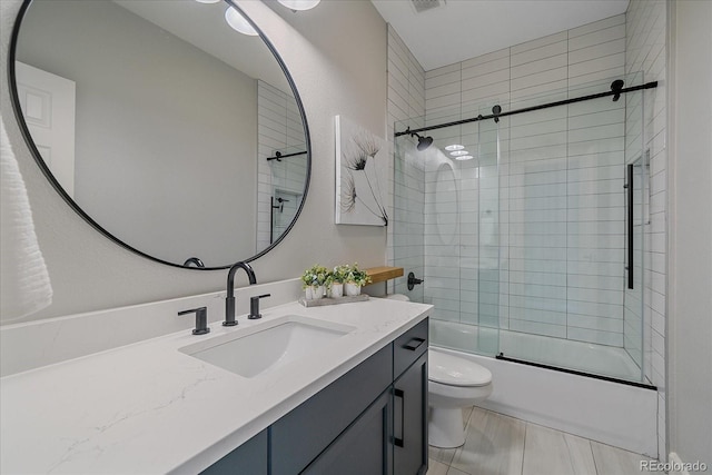 bathroom featuring combined bath / shower with glass door, visible vents, toilet, and vanity