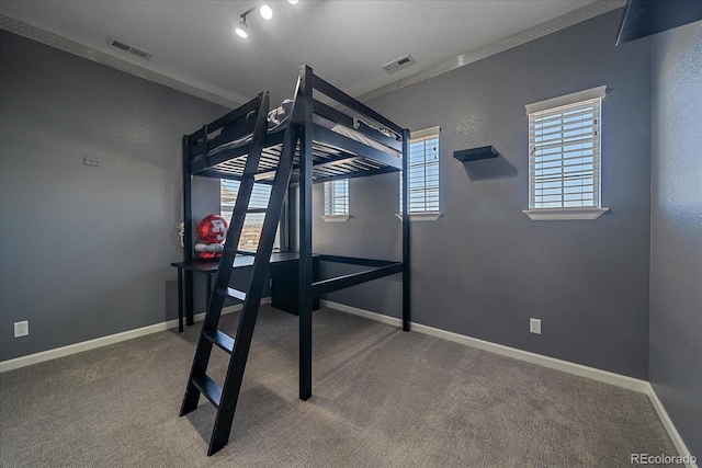 unfurnished bedroom with visible vents, baseboards, multiple windows, and carpet floors