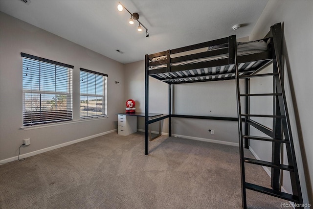 unfurnished bedroom featuring visible vents, baseboards, track lighting, and carpet flooring