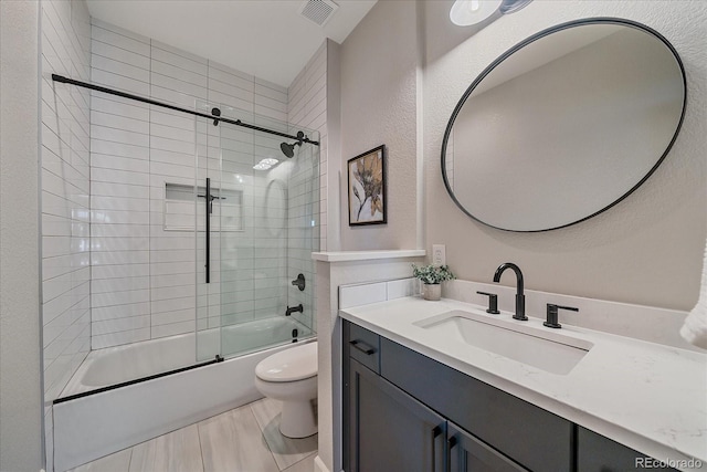 bathroom with combined bath / shower with glass door, visible vents, toilet, and vanity