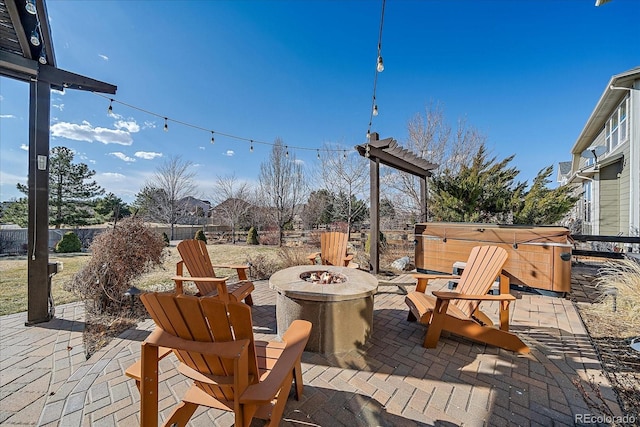 view of patio / terrace featuring fence, a hot tub, and an outdoor fire pit