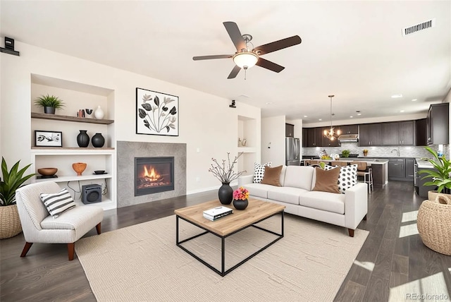 6370 Twilight Ave, Firestone, CO 80504 - living area featuring dark wood-type flooring, built in features, a ceiling fan, a tiled fireplace, and recessed lighting