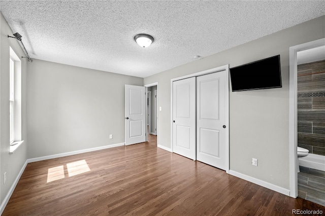 1765 S Endicott St, Lakewood, CO 80232 - unfurnished bedroom with wood finished floors, a closet, baseboards, a textured ceiling, and ensuite bathroom