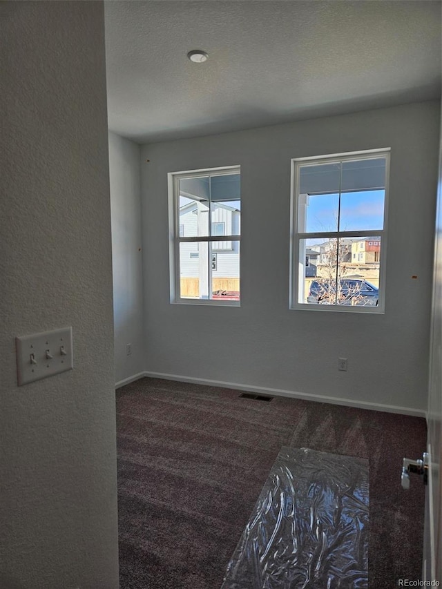 carpeted empty room featuring a textured ceiling