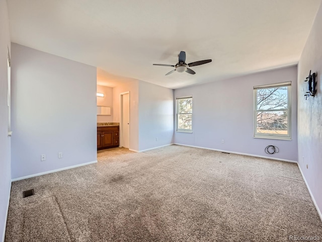 unfurnished bedroom featuring light carpet, a ceiling fan, visible vents, and baseboards